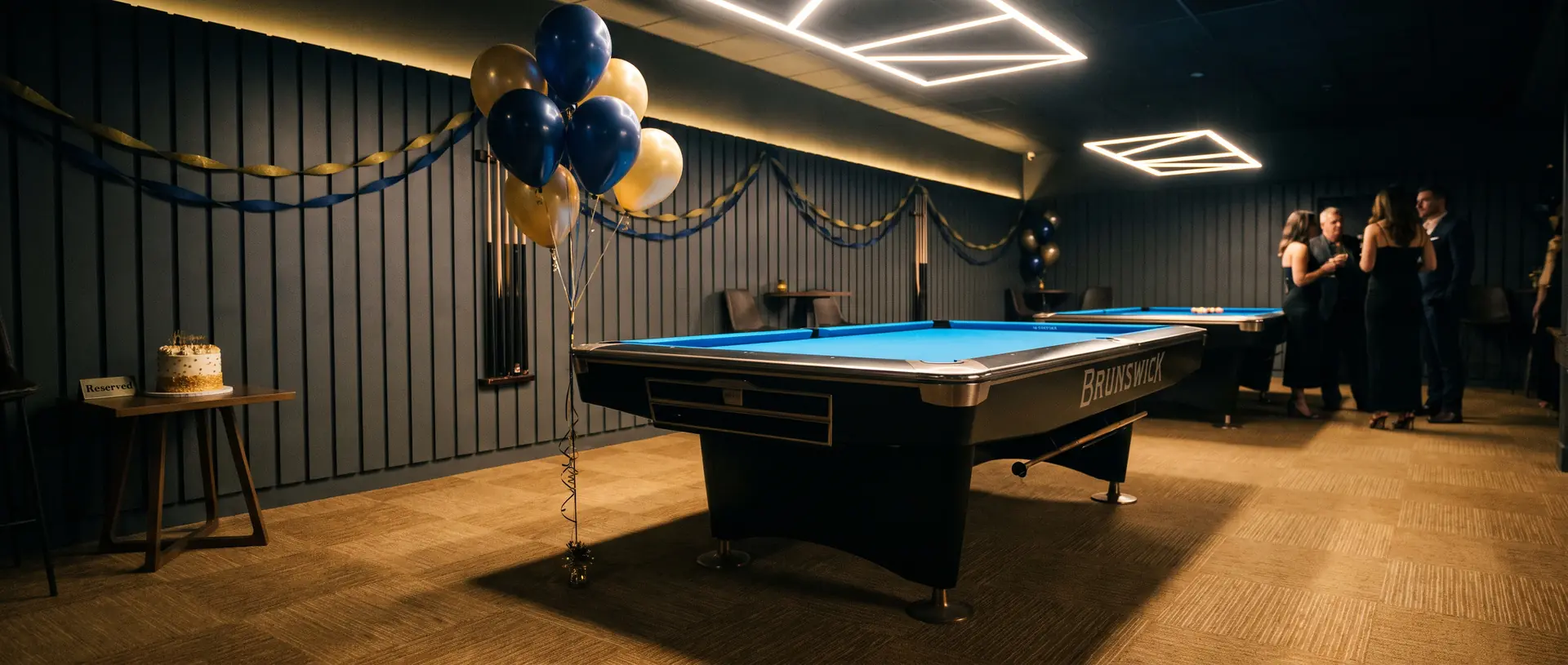 A Komic Karma pool table set up for a private party with balloons, streamers and a cake