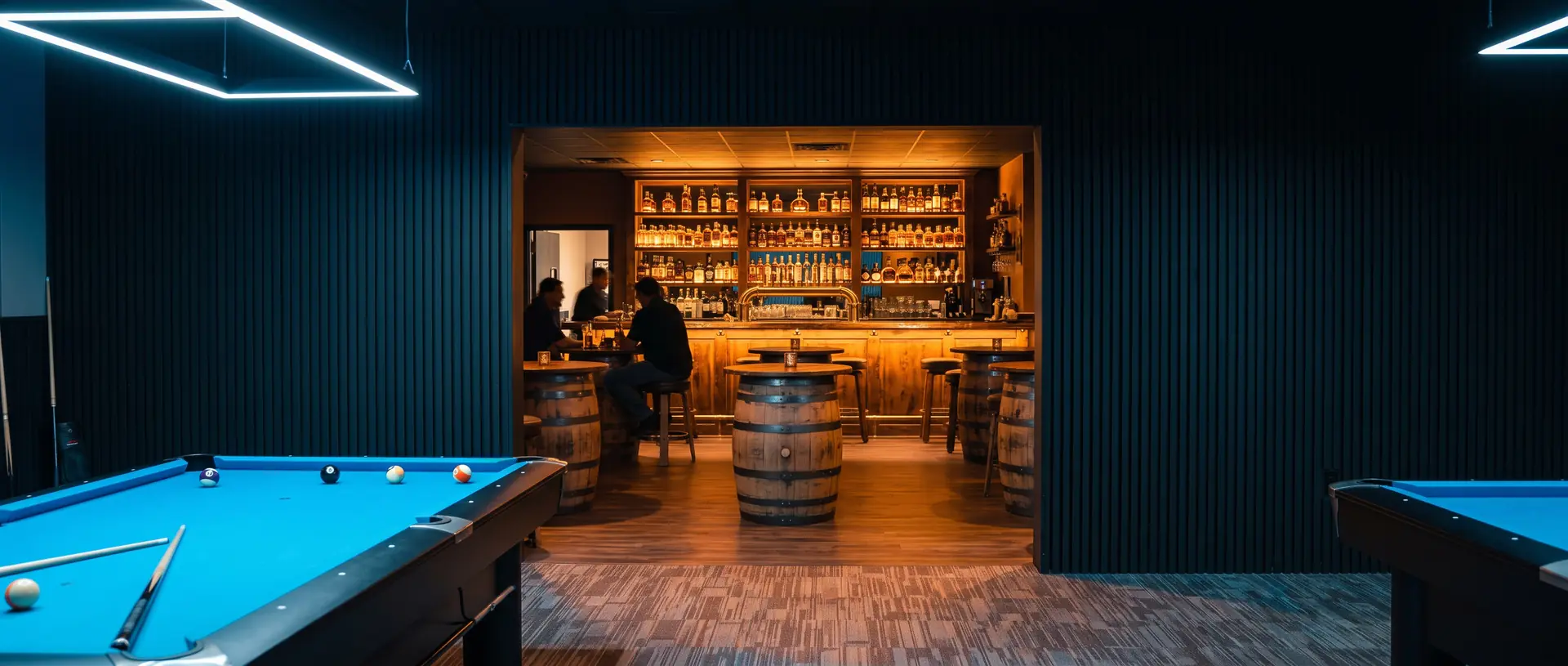 Looking through the opening cut in the wall between Komic Karma's blue-lit game room and Barrel's warm whiskey-barrel bar